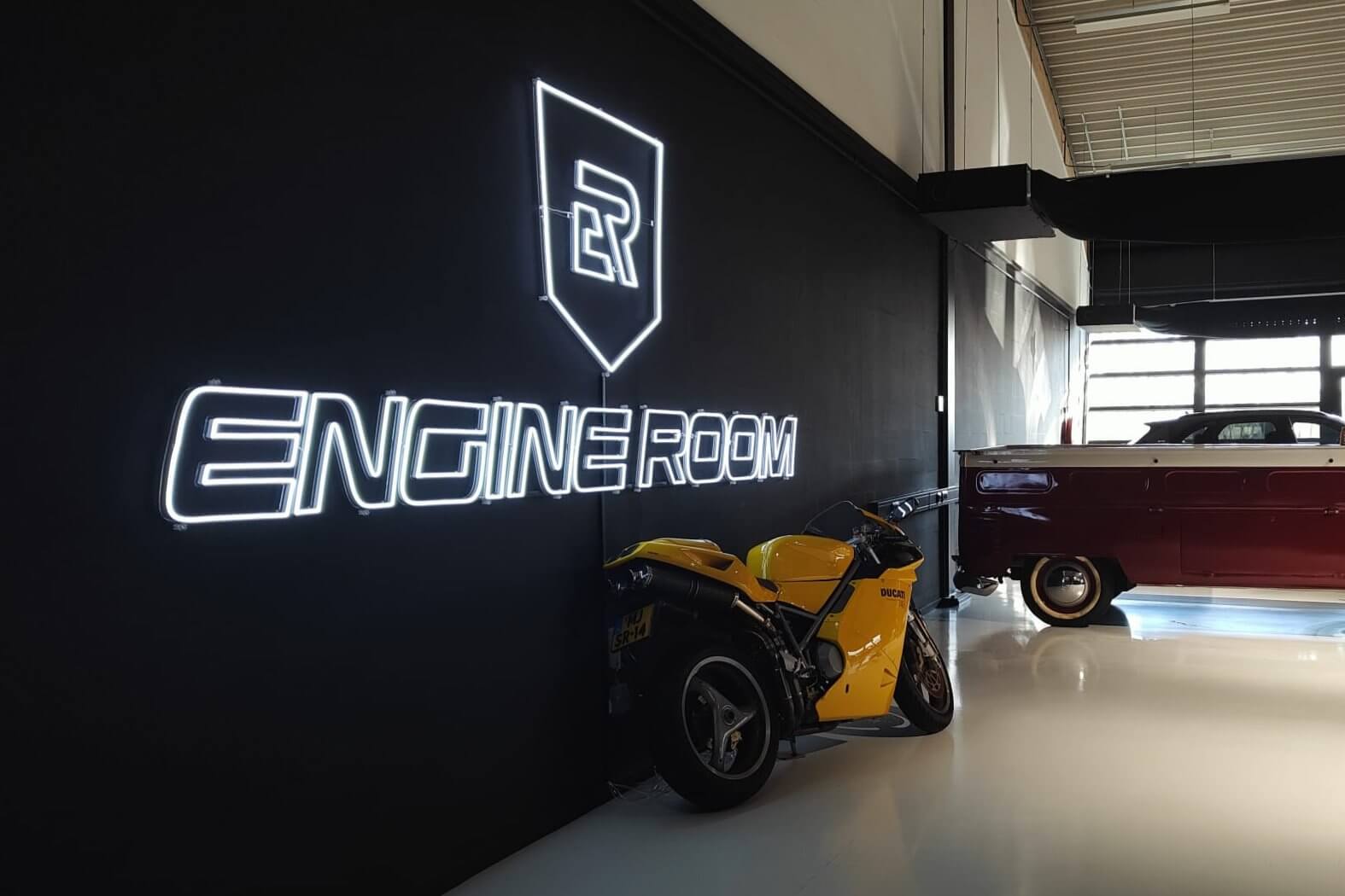 Neon lichtreclame voor autozaak Engine Room, ontworpen om de merknaam krachtig zichtbaar te maken in een industriële omgeving